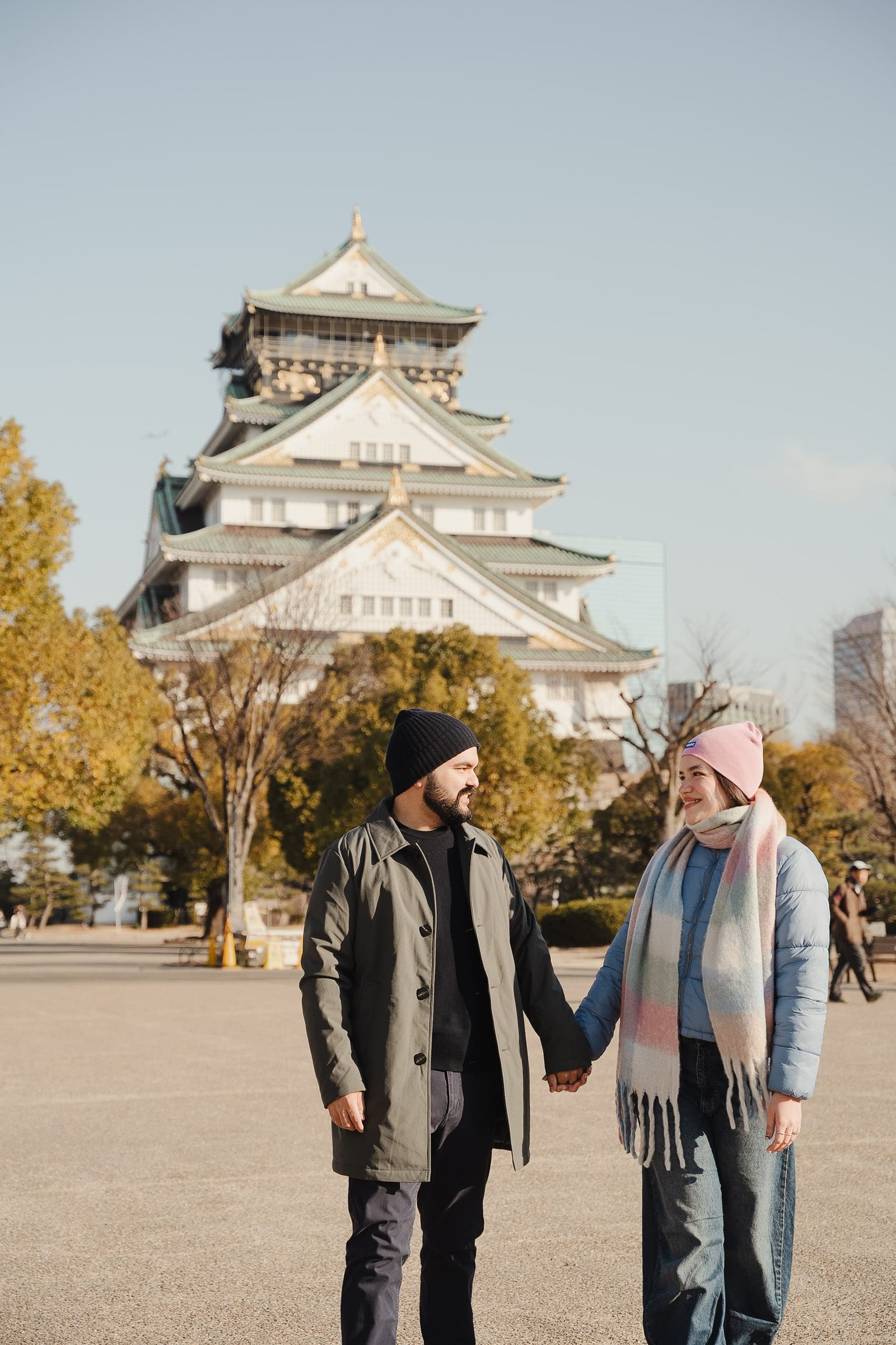 Couple holding hands with Osaka Castle in the background