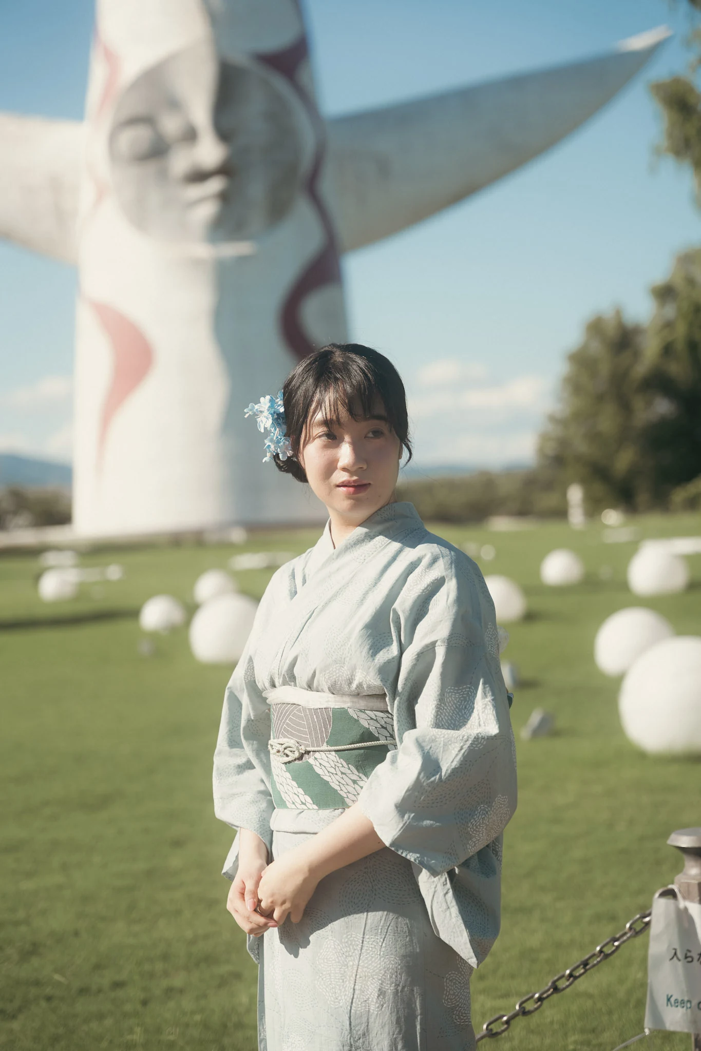 Woman in a light kimono beside the Tower of the Sun in Osaka