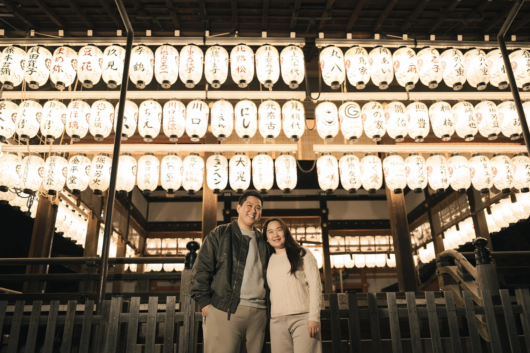 Couple standing beside illuminated lanterns at a Kyoto shrine at night