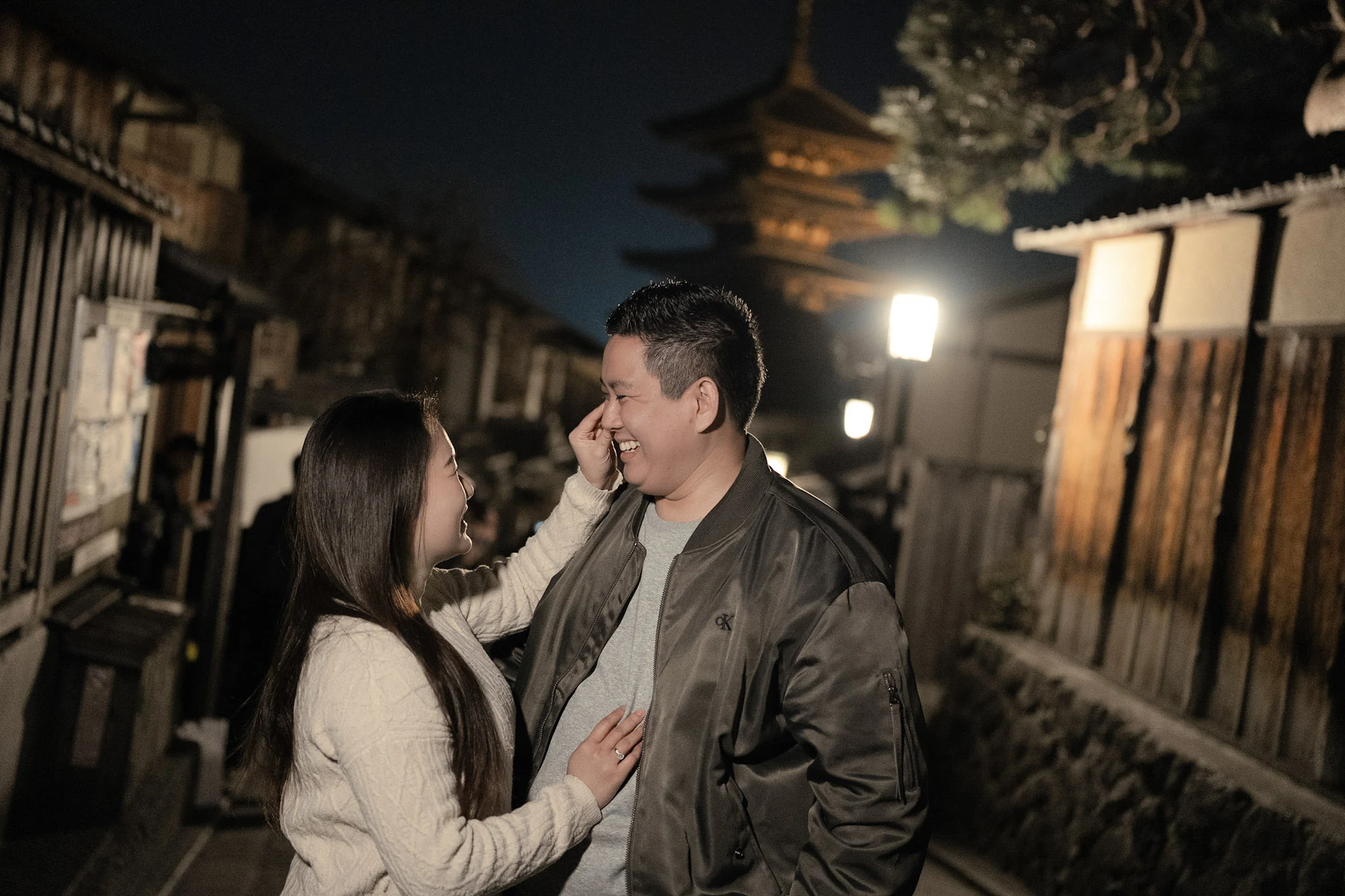Couple looking at each other on a softly lit traditional Kyoto street at night