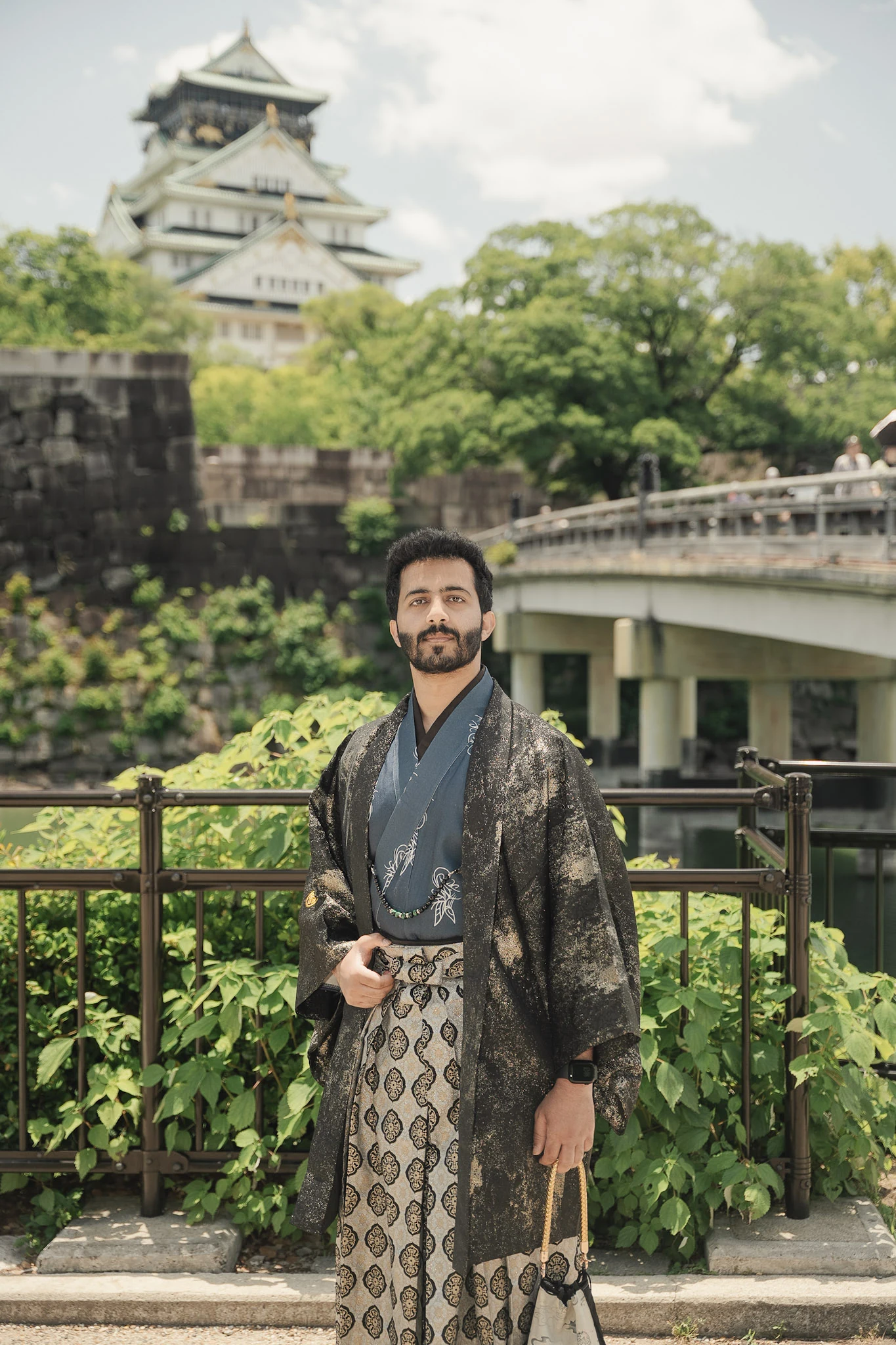 Man in a dark kimono with Osaka Castle in the background