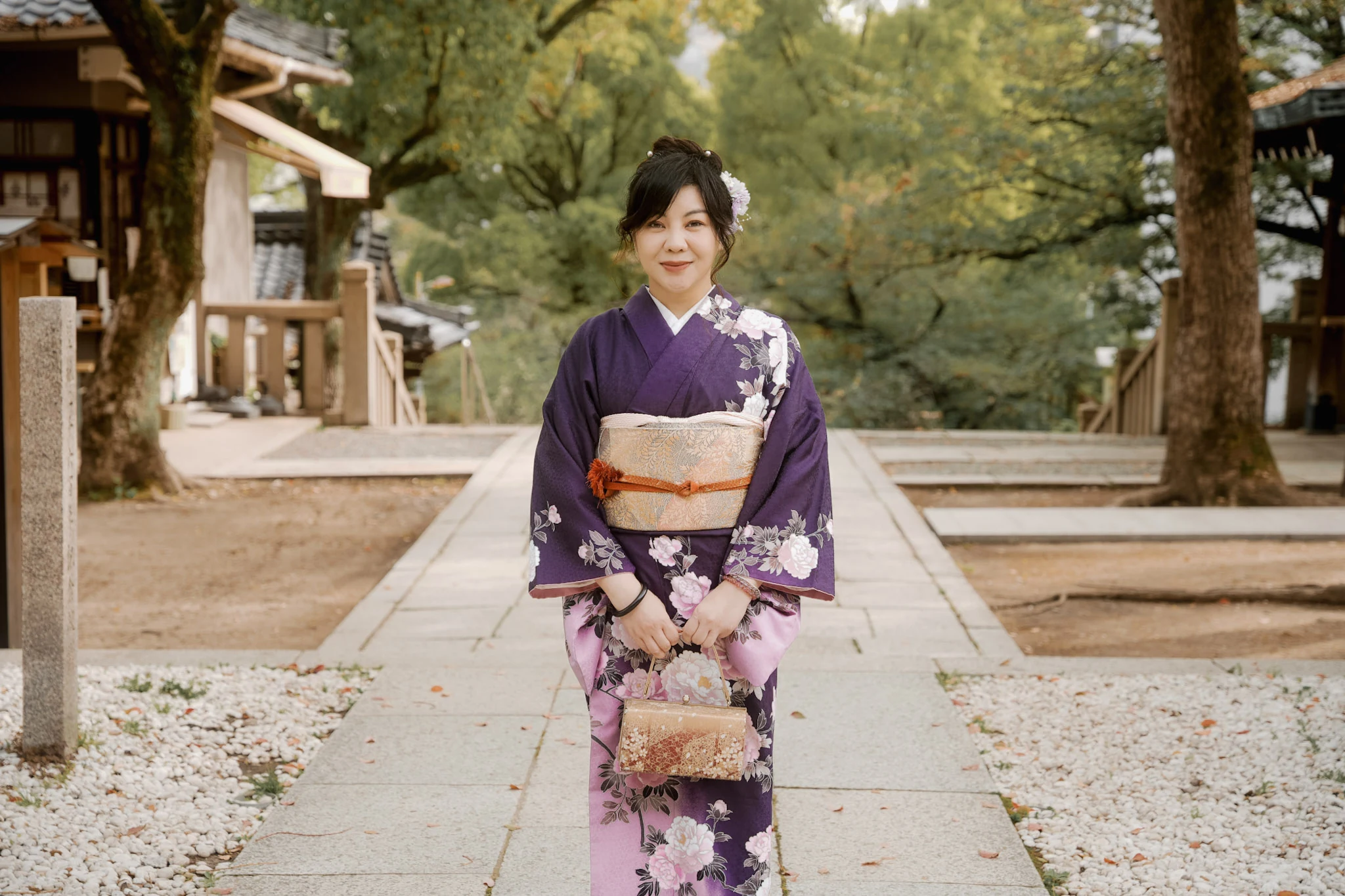 Woman in a purple floral kimono on a tree-lined shrine path